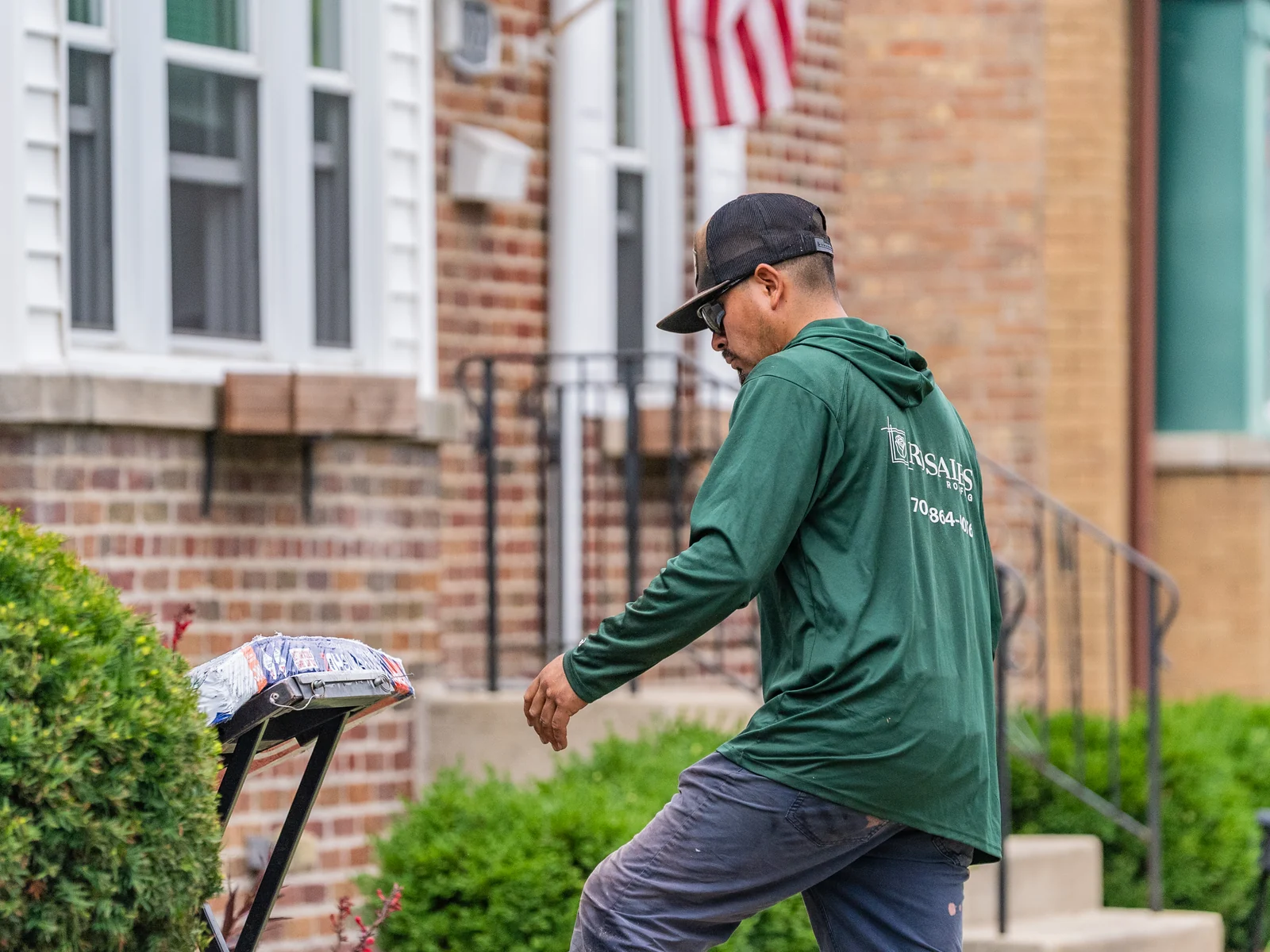 Rosales Roofing crew member loading shingle bundles onto the ladder hoist in Oak Forest, Illinois