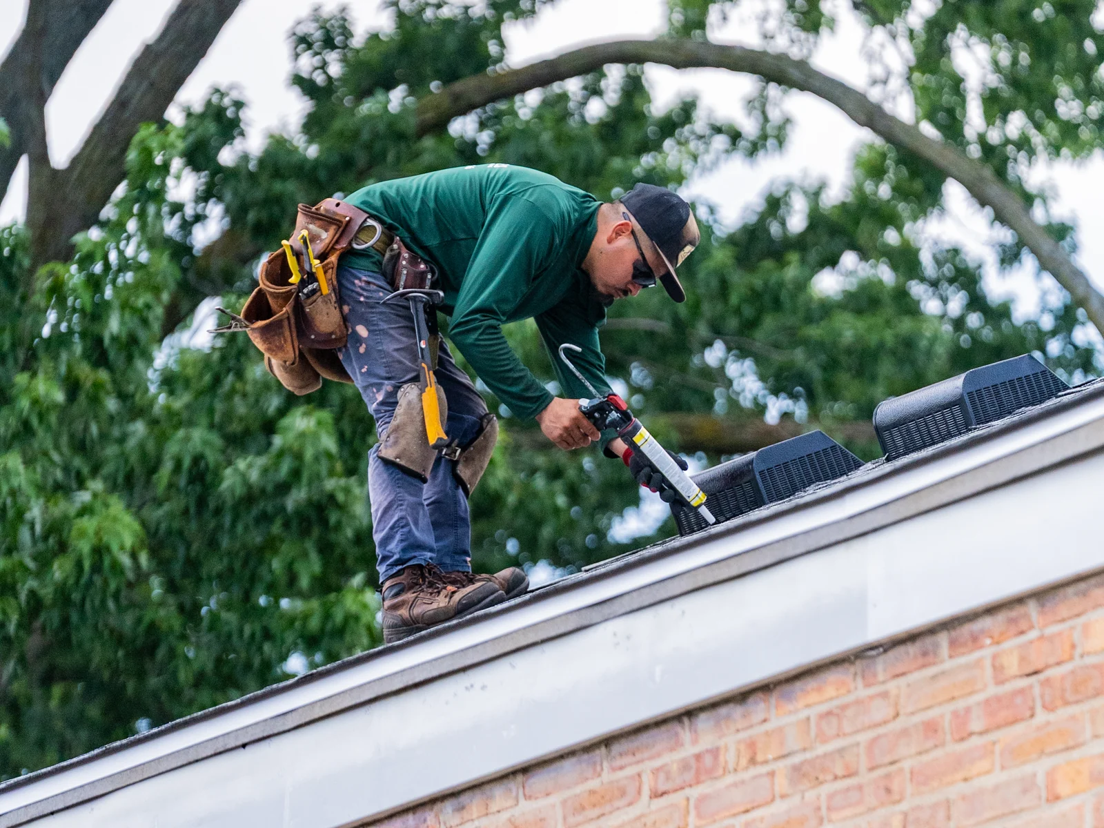 Rosales Roofing crew member sealing along a ridge vent on a finished shingle roof in Worth, Illinois