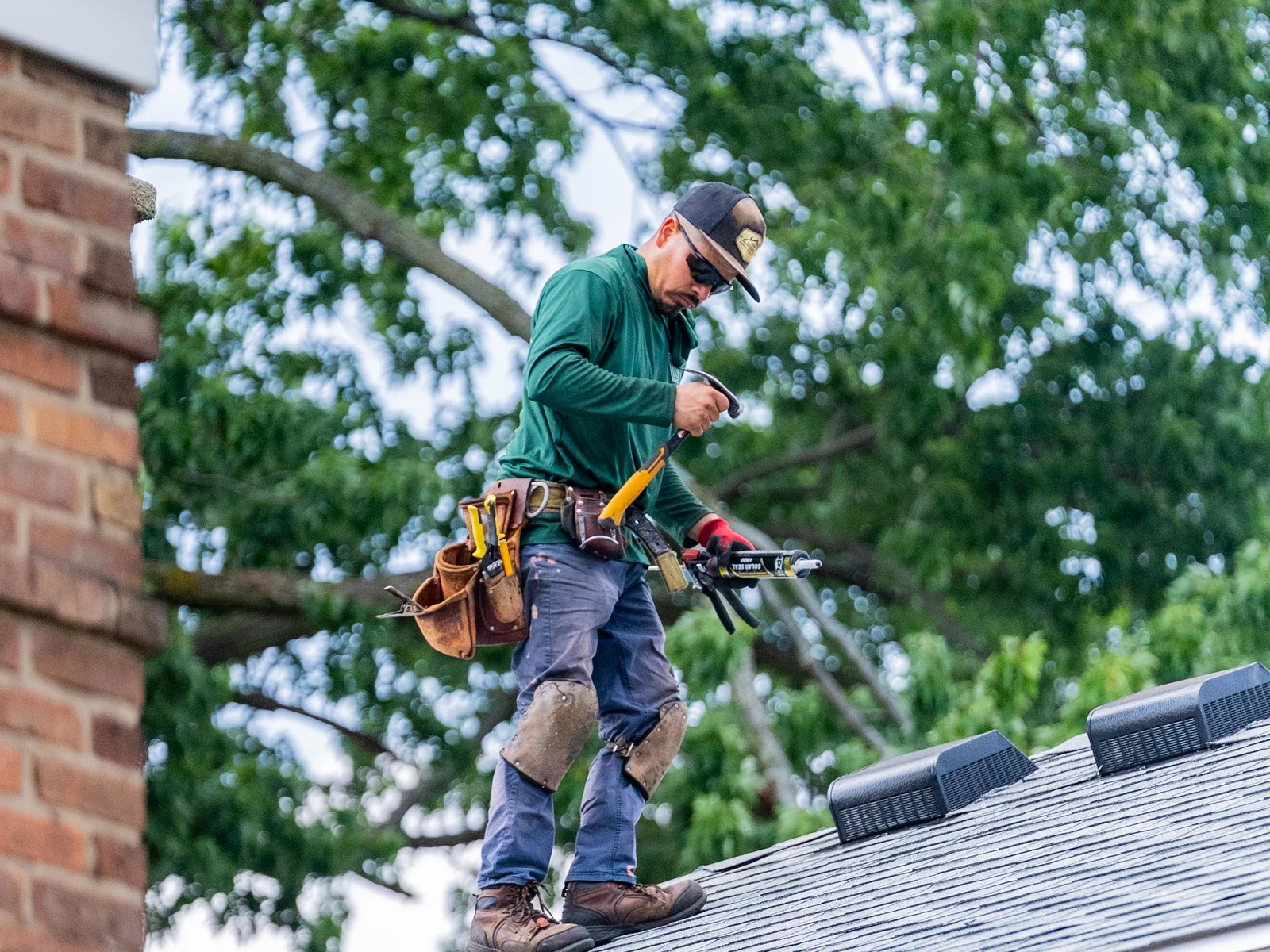 Rosales Roofing crew member on a finished shingle roof beside the chimney in Plainfield, Illinois